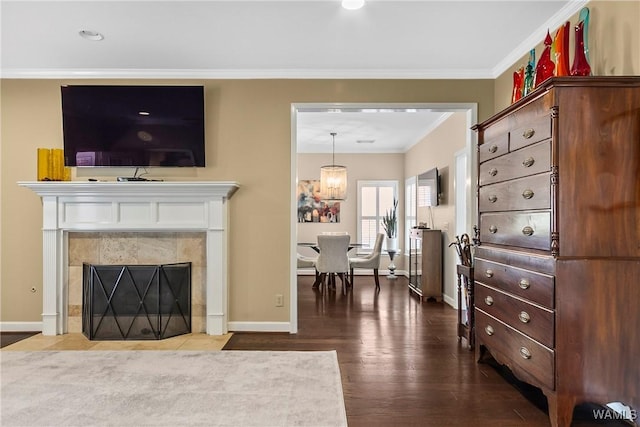 living room with dark wood-type flooring, a tile fireplace, crown molding, and baseboards