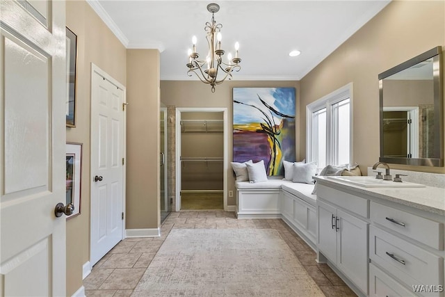 bathroom with baseboards, a spacious closet, crown molding, vanity, and a notable chandelier