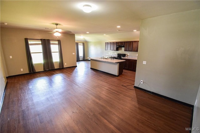 kitchen featuring black stove, dark brown cabinets, ceiling fan, dark wood-type flooring, and an island with sink