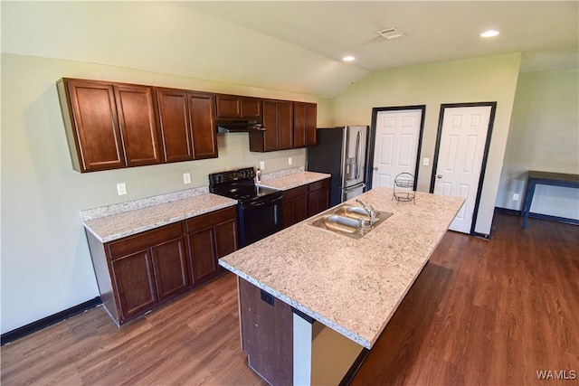 kitchen featuring electric range, dark wood-type flooring, stainless steel fridge, vaulted ceiling, and a center island with sink