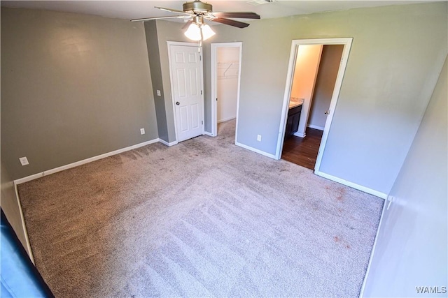 unfurnished bedroom with ensuite bathroom, carpet flooring, ceiling fan, a spacious closet, and a closet