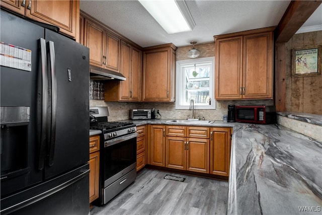 kitchen featuring sink, black fridge, stainless steel range with gas cooktop, and a textured ceiling