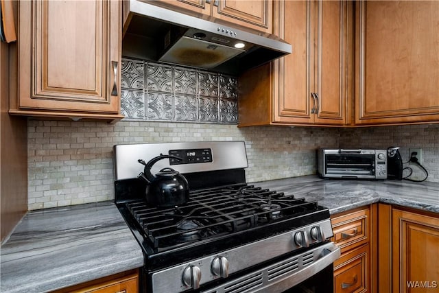 kitchen with dark stone countertops, tasteful backsplash, and stainless steel gas range oven