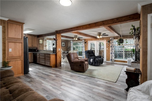 living room with light wood-type flooring, french doors, wooden walls, beam ceiling, and a textured ceiling