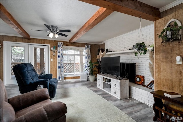 living room featuring wooden walls, a textured ceiling, ceiling fan, beam ceiling, and dark wood-type flooring