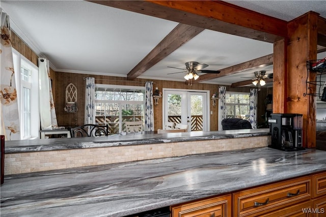 kitchen featuring french doors, wooden walls, ceiling fan, ornamental molding, and beamed ceiling