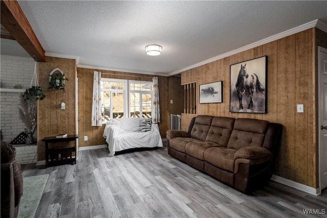 living room featuring a textured ceiling, hardwood / wood-style floors, ornamental molding, and wooden walls