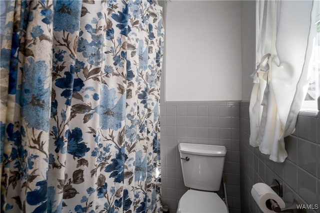 bathroom with tile walls, a shower with curtain, and toilet