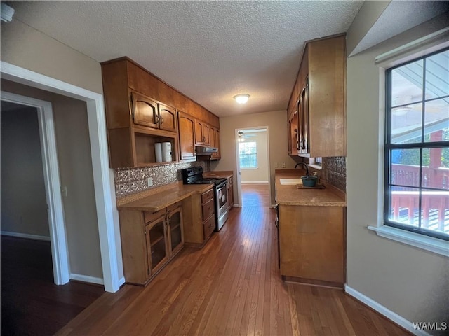 kitchen with a textured ceiling, backsplash, dark hardwood / wood-style floors, and electric stove