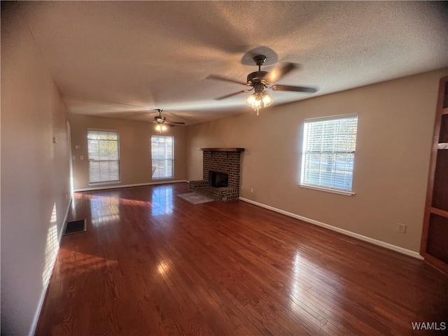 unfurnished living room with dark hardwood / wood-style floors, ceiling fan, a textured ceiling, and a brick fireplace