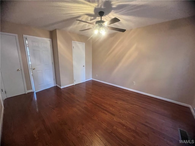 unfurnished bedroom with ceiling fan and dark wood-type flooring