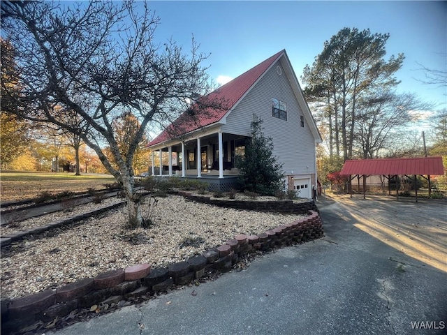 view of side of property with covered porch, a garage, and a carport