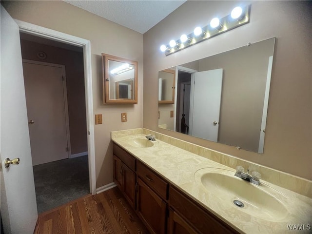 bathroom with hardwood / wood-style floors, vanity, and a textured ceiling