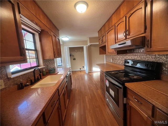 kitchen with light hardwood / wood-style floors, sink, stainless steel appliances, and tasteful backsplash