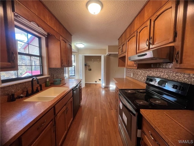 kitchen with appliances with stainless steel finishes, light wood-type flooring, backsplash, a textured ceiling, and sink