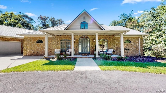 view of front of home featuring an attached garage, covered porch, a front lawn, and brick siding