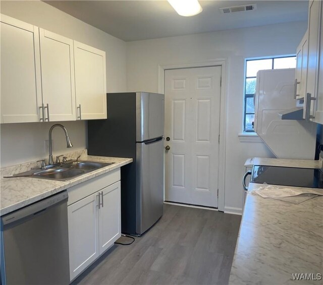 kitchen featuring visible vents, light countertops, appliances with stainless steel finishes, white cabinets, and a sink