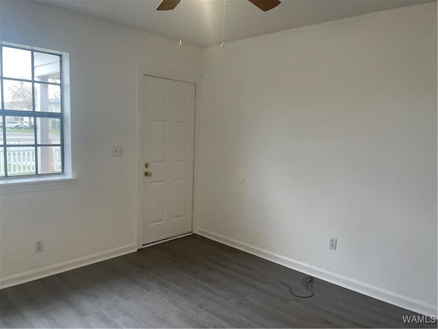 unfurnished room featuring a ceiling fan, dark wood-style flooring, and baseboards