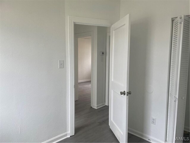 hallway with dark wood-type flooring and baseboards