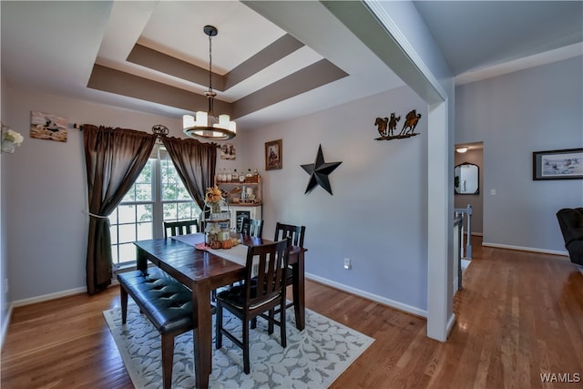 dining space with a chandelier, wood-type flooring, and a tray ceiling