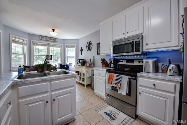 kitchen featuring light tile patterned flooring, white cabinetry, sink, and appliances with stainless steel finishes