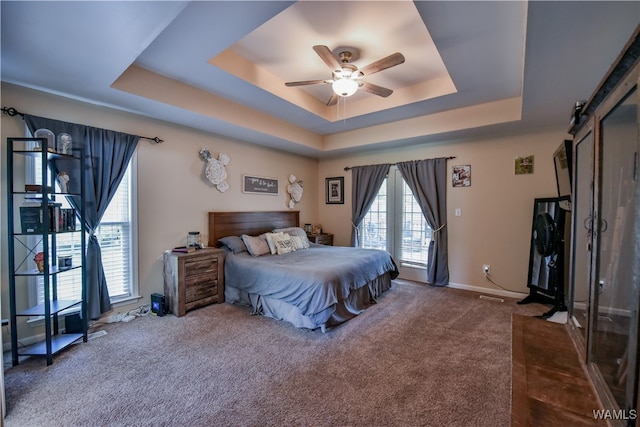 bedroom with carpet, ceiling fan, a barn door, and a tray ceiling