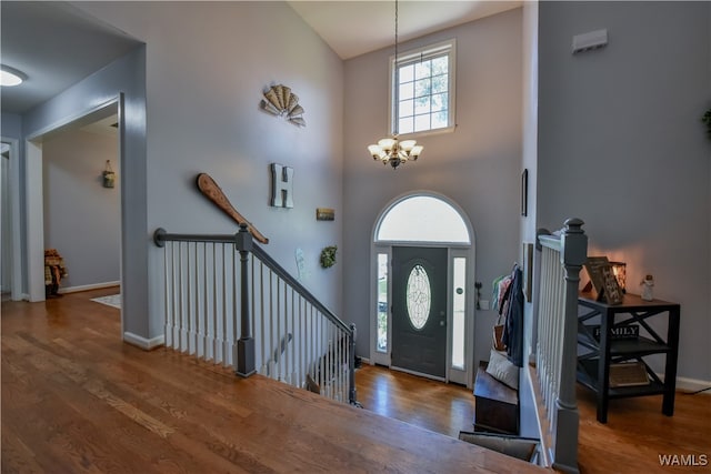 entrance foyer with dark wood-type flooring, a high ceiling, and a notable chandelier