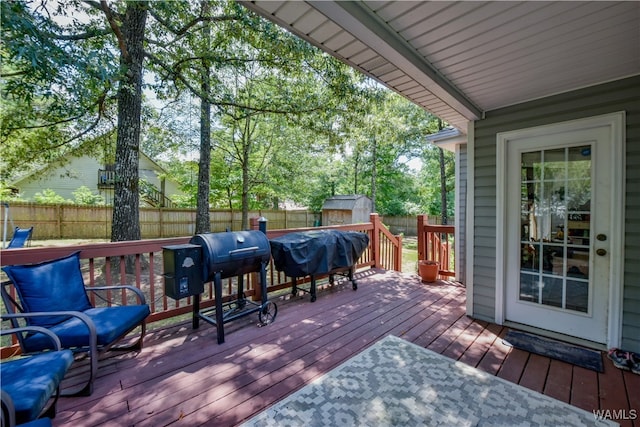 wooden terrace featuring a grill and a storage unit