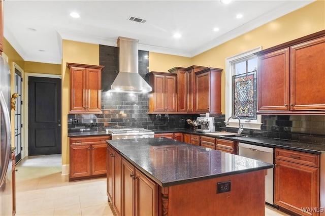 kitchen with appliances with stainless steel finishes, a kitchen island, wall chimney range hood, decorative backsplash, and sink