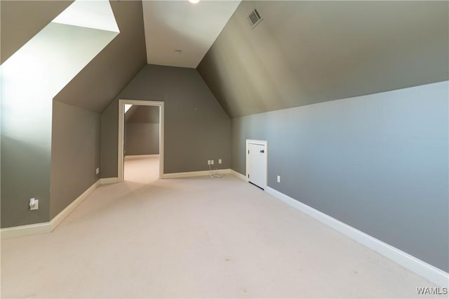 additional living space featuring light colored carpet and lofted ceiling