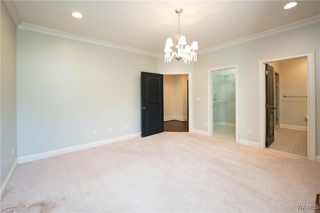 unfurnished bedroom with a walk in closet, carpet floors, a closet, ornamental molding, and ensuite bathroom