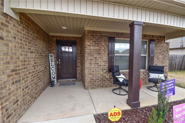 property entrance featuring covered porch and brick siding