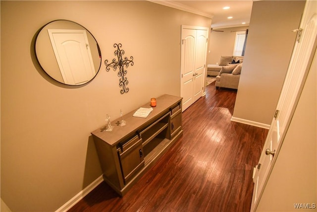 hall with dark wood-style floors, recessed lighting, ornamental molding, and baseboards