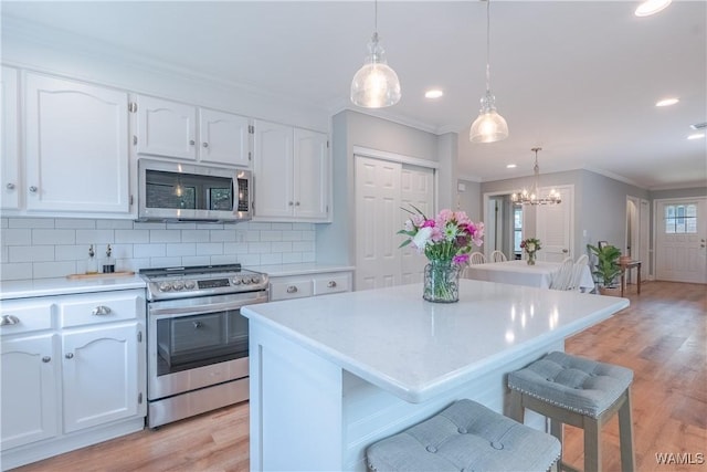 1603 Quail Run Dr, Tuscaloosa, AL 35406 - kitchen with stainless steel appliances, white cabinetry, ornamental molding, light countertops, and light wood-style flooring