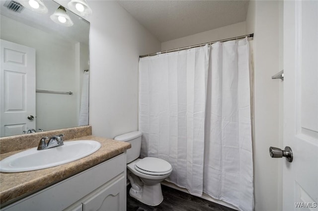 bathroom featuring vanity, wood-type flooring, toilet, and a textured ceiling