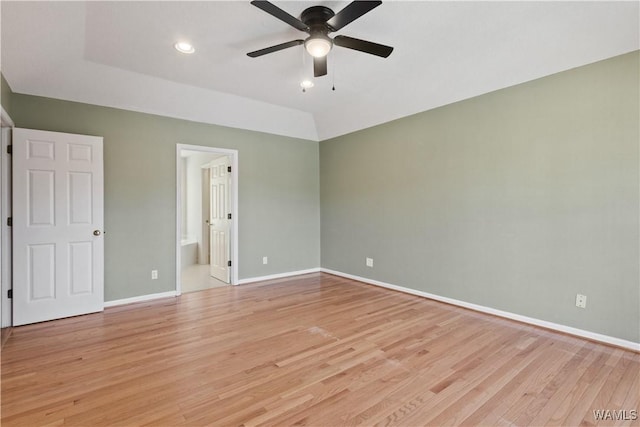 unfurnished bedroom with lofted ceiling, a ceiling fan, connected bathroom, light wood finished floors, and baseboards