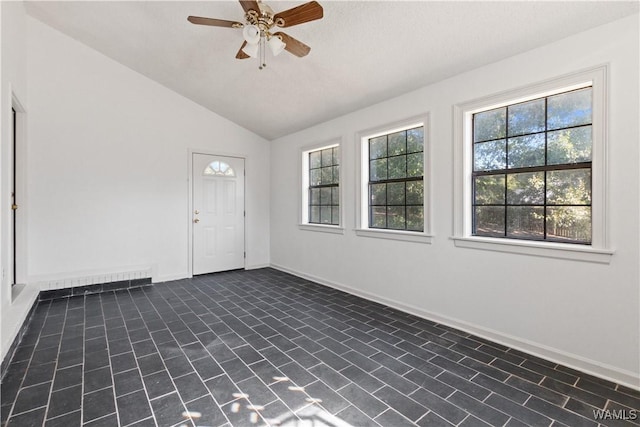 interior space featuring baseboards, a healthy amount of sunlight, a ceiling fan, and vaulted ceiling