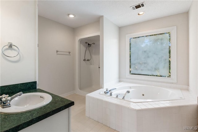 bathroom featuring visible vents, a textured ceiling, recessed lighting, a tub with jets, and walk in shower