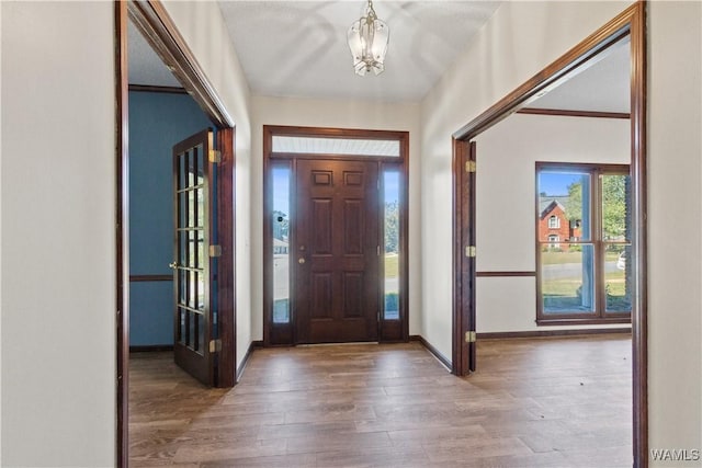 foyer with a chandelier, baseboards, and wood finished floors