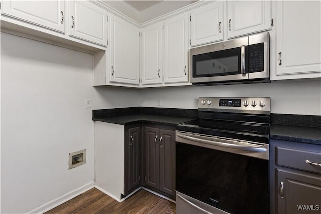 kitchen featuring dark countertops, baseboards, dark wood finished floors, appliances with stainless steel finishes, and white cabinetry