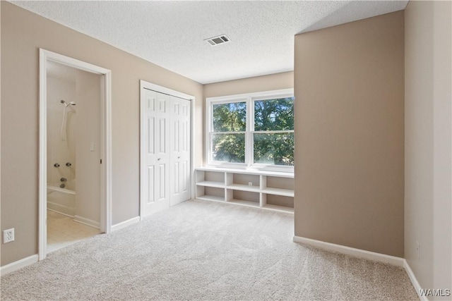 unfurnished bedroom with visible vents, baseboards, a textured ceiling, and carpet flooring