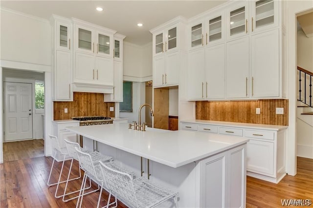 kitchen featuring a kitchen bar, white cabinetry, a center island with sink, and light hardwood / wood-style floors