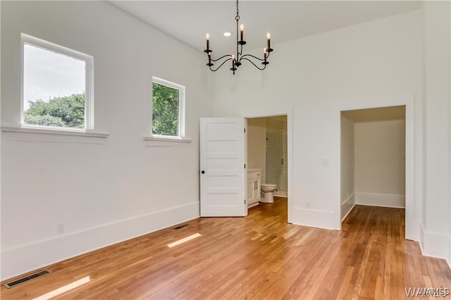 spare room with light hardwood / wood-style floors and a chandelier