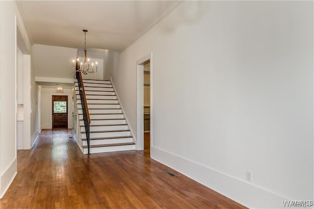 stairs featuring hardwood / wood-style flooring, crown molding, and an inviting chandelier