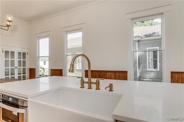 room details with a notable chandelier, wall oven, ornamental molding, and sink