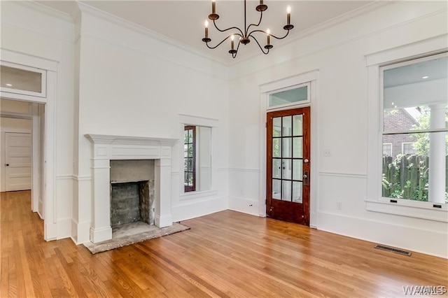 unfurnished living room with a notable chandelier, ornamental molding, and light hardwood / wood-style flooring