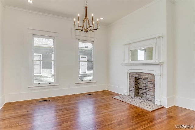 unfurnished living room with a fireplace, wood-type flooring, an inviting chandelier, and ornamental molding