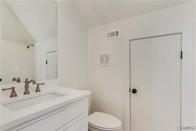 bathroom with vanity, vaulted ceiling, and toilet