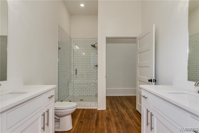 bathroom with hardwood / wood-style floors, vanity, an enclosed shower, and toilet