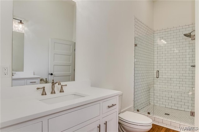 bathroom with toilet, hardwood / wood-style floors, vanity, and walk in shower